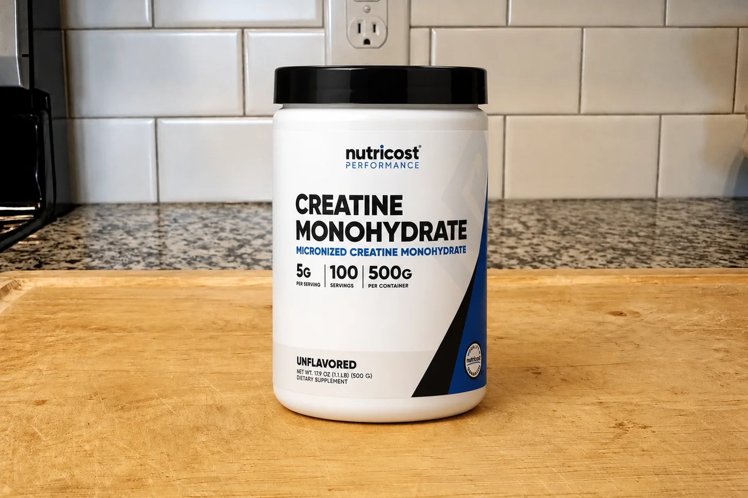 A tub of Nutricost Creatine Monohydrate micronized powder on our kitchen counter, 500 g